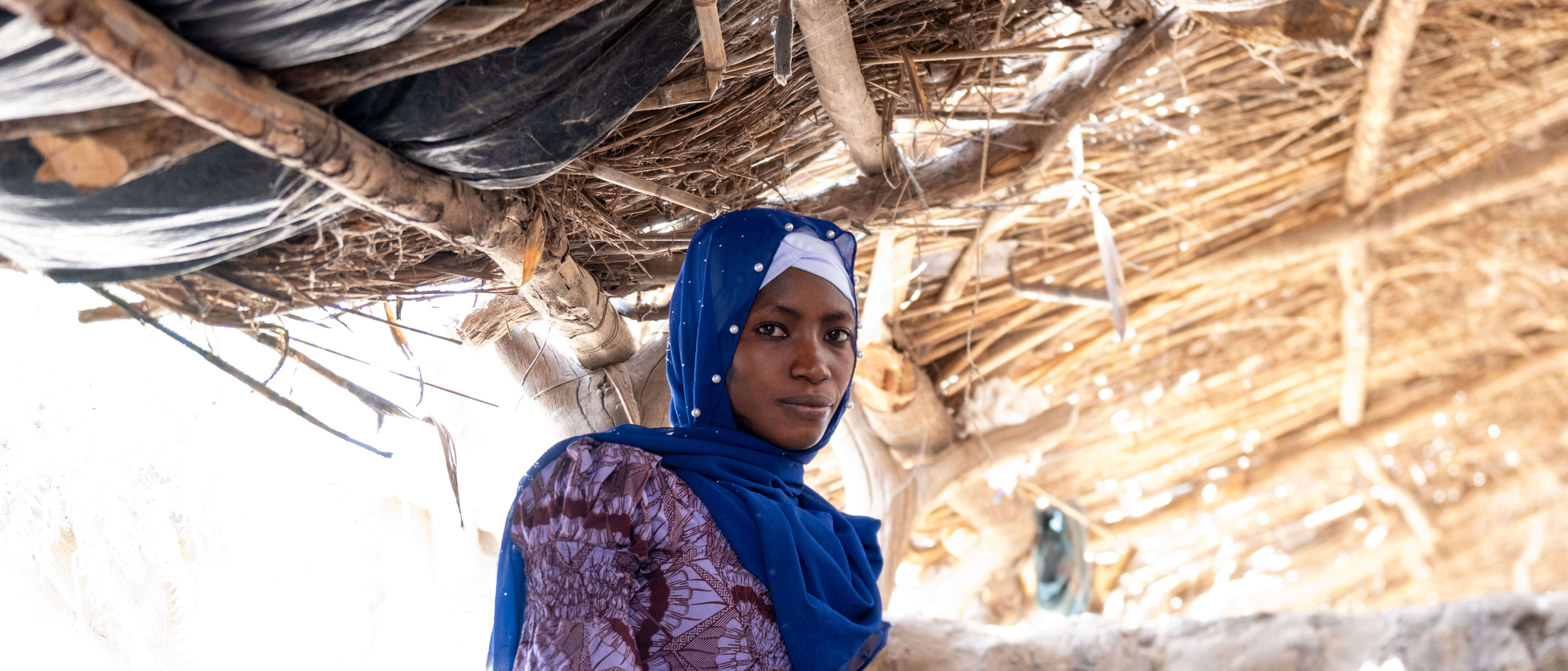 A woman poses for a photo in a makeshift shelter in Mali.